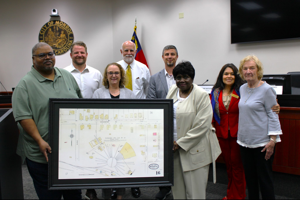 The Winchester Revitalization Committee holds framed plans for the roundhouse at a meeting.